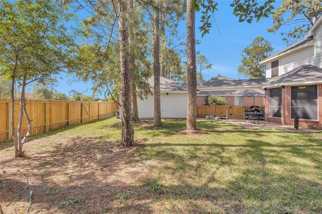 Spacious two-car garage with a charming brick exterior, nestled among tall trees for added privacy. The fenced area offers a secluded outdoor space, perfect for relaxation or entertaining.