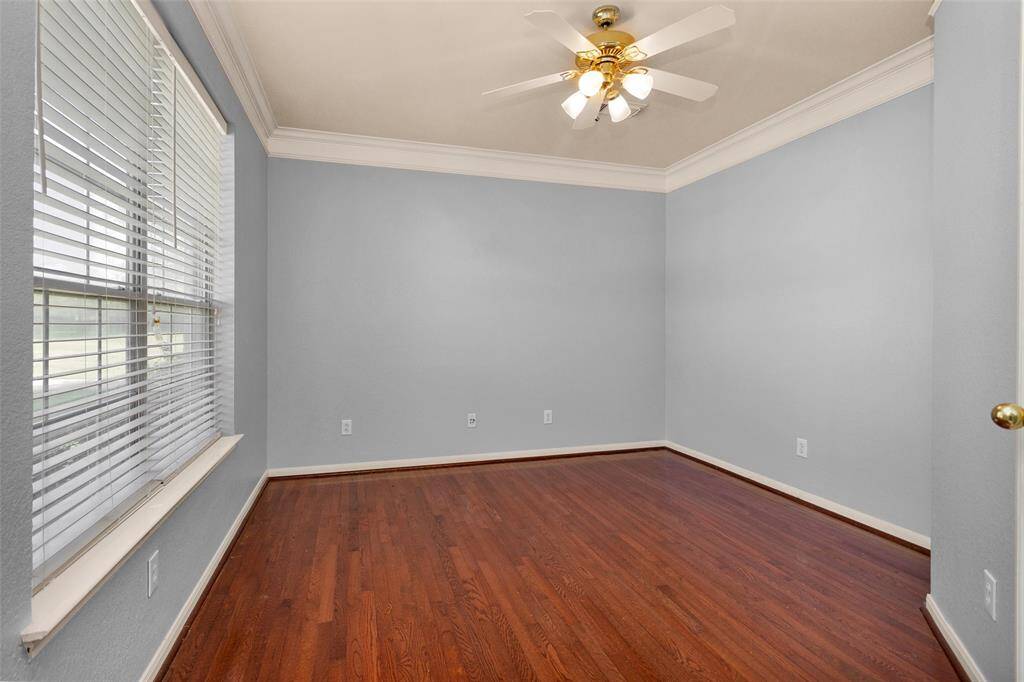 Discover a bright and inviting room featuring elegant wood flooring, soft gray walls, and abundant natural light from large windows. Perfect for a home office or cozy retreat.