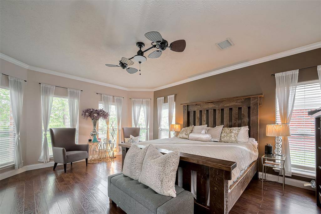 The primary bedroom featuring hardwood floors and ample natural light from multiple windows