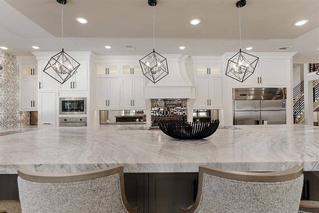 This kitchen is meant for a culinary enthusiast, with a leathered quartzite island, breakfast bar, soft close cabinetry and drawers, 6 burner gas range with griddle and pot filler.