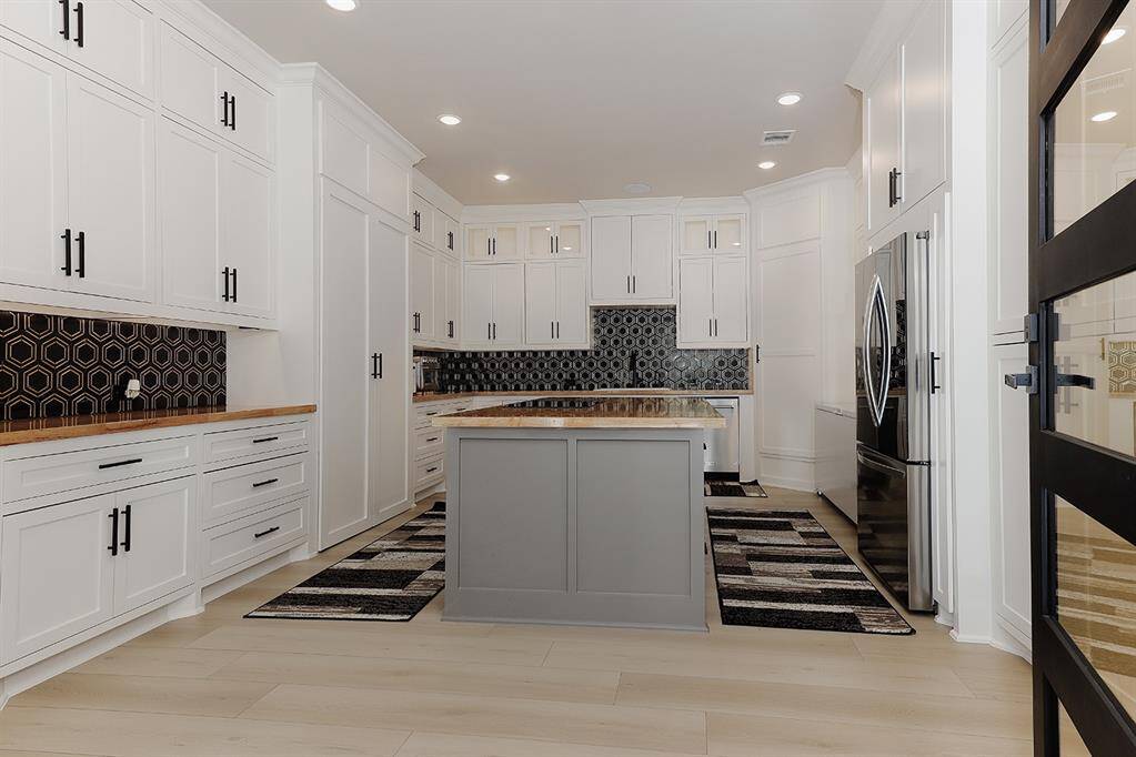 The catering kitchen has an induction cooktop, 2nd dishwasher, butcher block island and built-in refrigerator.