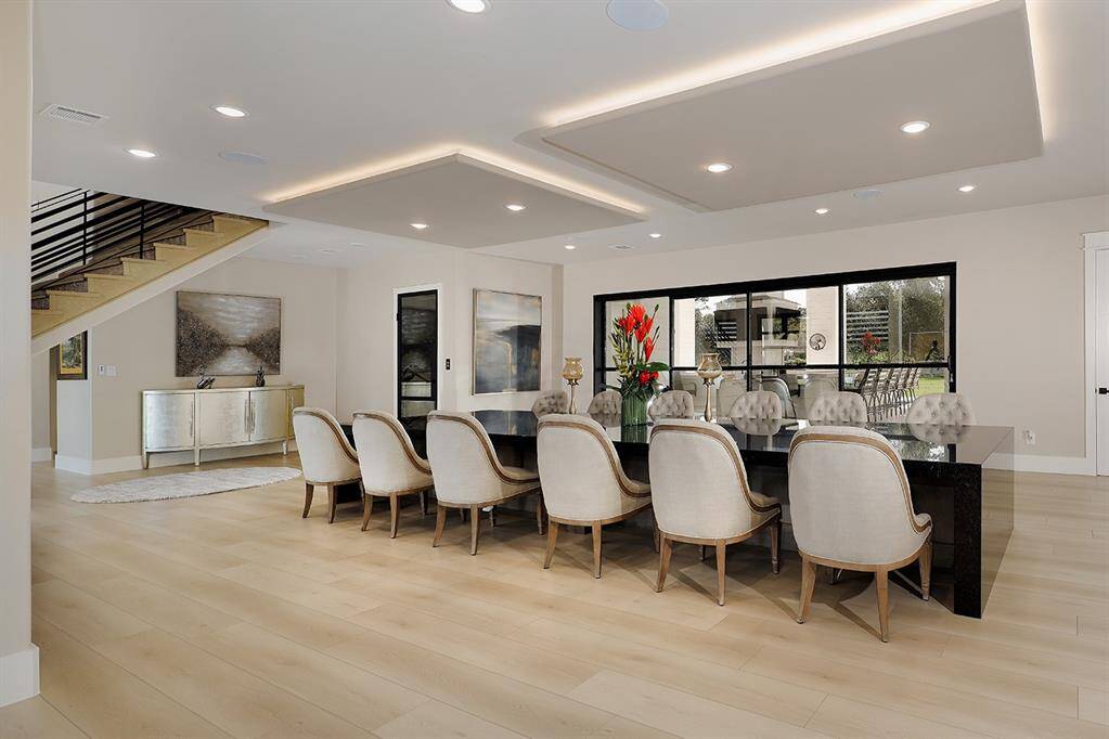 This formal dining room features a custom table with seating for 12, and glass Nano doors behind that offer a seamless transition between indoor and outdoor spaces for entertaining.