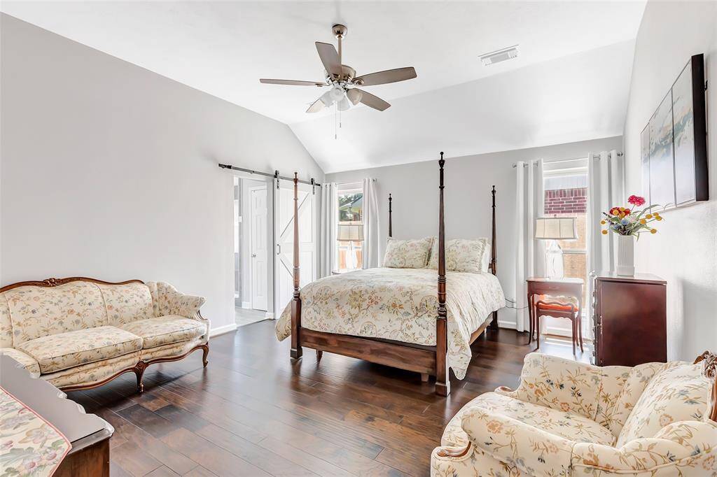 The primary bedroom is large and features a barn door that leads into the en-suite bathroom.
