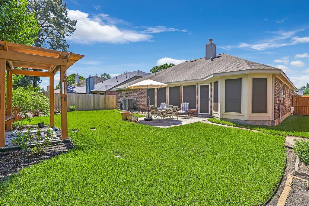 The spacious backyard with a pergola. The home features solar screens on all the windows.