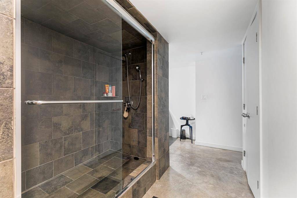 Oversized walk-in shower with frameless glass, dual shower head and slate surround.