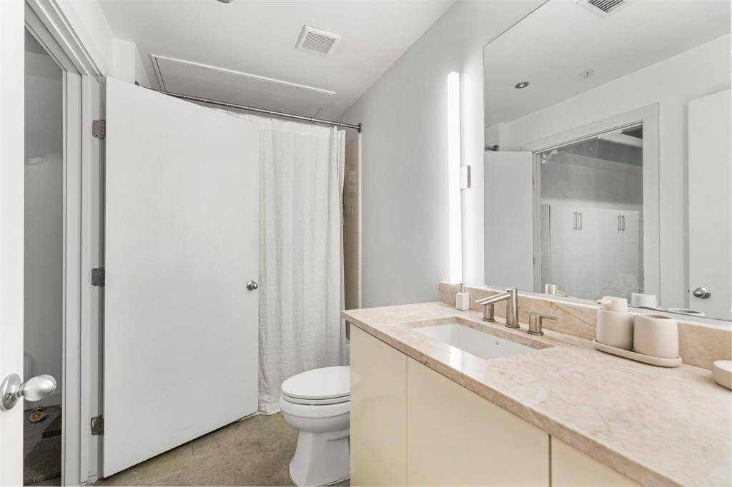 First floor bathroom features quartzite countertops, custom cabinetry, undermount sink, tub/shower combination, and modern fixtures and lighting.