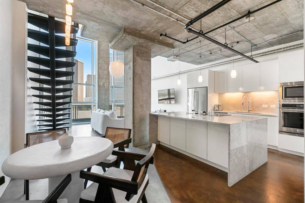 Polished concrete flooring, floor to ceiling windows, exposed ductwork, concrete ceilings, and floating metal staircase showcase this lofty floor plan.