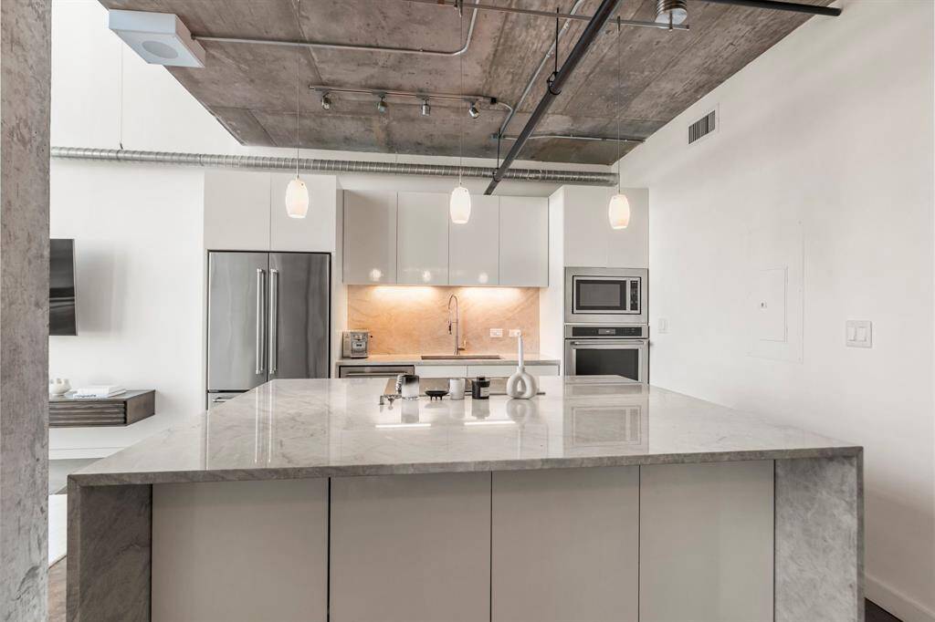 So many modern updates in this beautifully remodeled kitchen. Huge island cooktop with downdraft vent, Beautiful marble island extended with waterfall