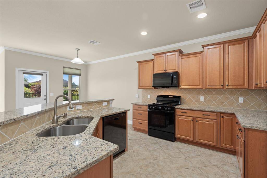 Gleaming upgraded granite and a high bar beautifully define the space between the kitchen and Gathering Room. Warm-toned cabinets—some 42", some 36"—add visual interest and offer plenty of drawers for easy, organized living.