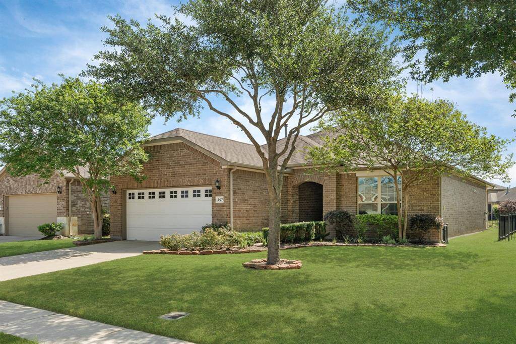 A welcoming arched entry, peek-a-boo garage windows, and crisp paver borders make this home pop from every angle. The crepe myrtles and oak tree bring just the right mix of shade and charm—nature showing off a little!