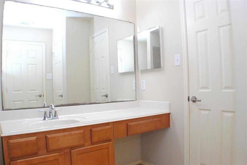 Primary bath vanity area and door to one of the primary closets