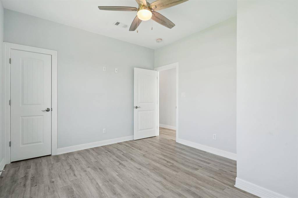Inviting second bedroom featuring sleek flooring, ample natural light, and a modern ceiling fan for comfort.