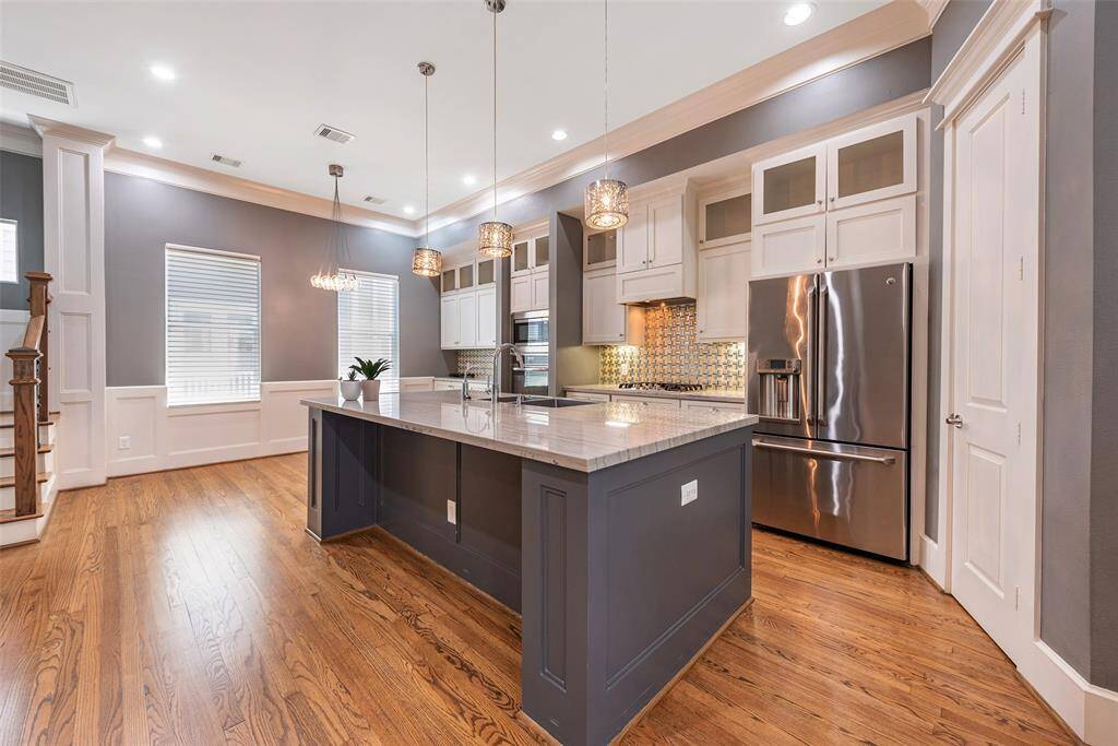 Another view of the kitchen with a large stainless sink, gas cooktop, and the dining room. What a lovely space to gather around with a beverage!