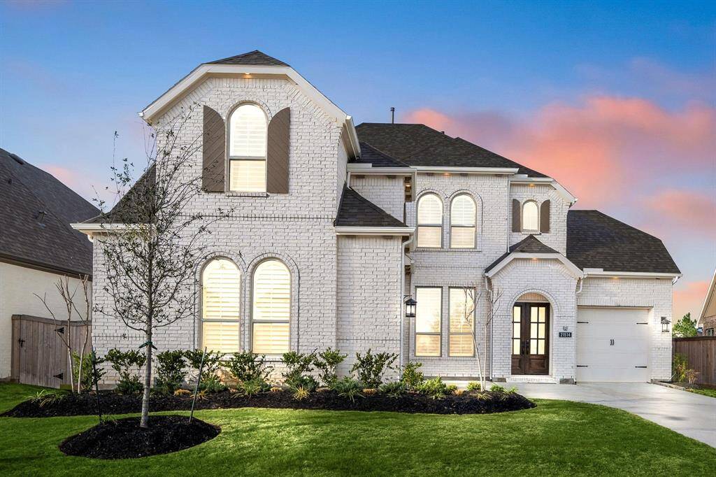 This stunning home features a modern exterior with warm lighting that enhances its inviting appeal, perfect for comfortable family living.