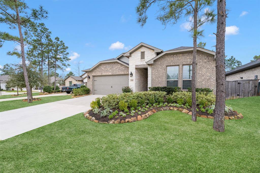 This charming home features a brick exterior, Austin stone accent, a double garage, and a manicured front garden. The inviting entrance is complemented by modern lighting.