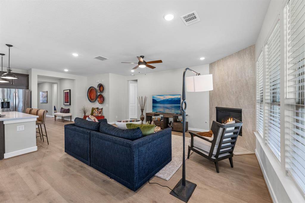 Another view of the living room and the tiled corner fireplace. The hallway ahead leads to the primary bedroom and laundry room