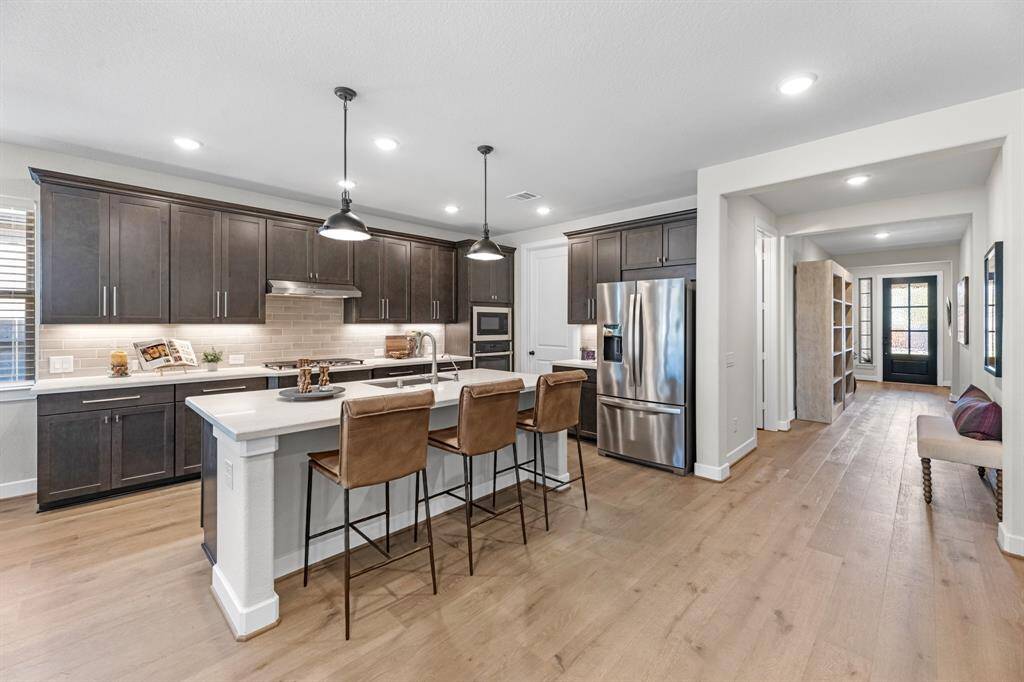 Stunning kitchen with wood cabinets, quartz counters, wood flooring, stainless appliances, hardware and walk-in pantry. The island is perfect for entertaining and being part of the conversation