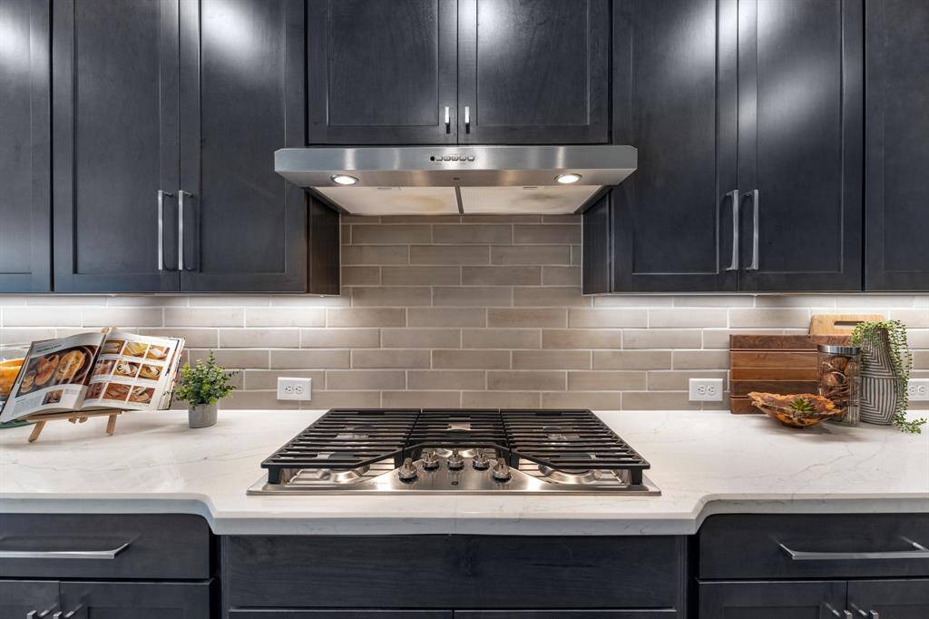 5 burner stainless gas cooktop, beautiful quartz counters and neutral tiled backsplash. This kitchen has a ton of storage and counter space-a chef's dream