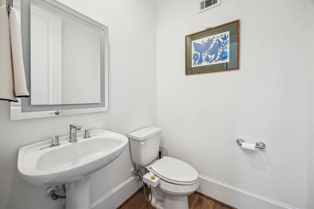 The powder bathroom is convenient for guests featuring a pedestal sink with upgraded fixtures and a framed mirror above and a bidet.