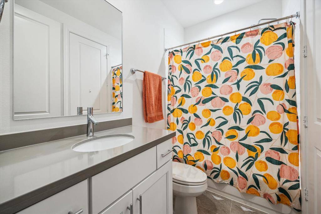This spotless private ensuite bathroom features an extended single-sink vanity with a full-width mirror above, along with a convenient tub and shower combination, offering both style and functionality for any guest.