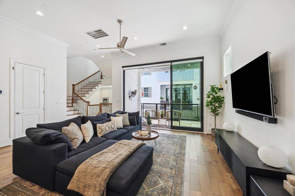 The family room offers an open, airy vibe thanks to a soaring ceiling with recessed lighting and a modern fan, and 10’ sliding glass doors that extend the living space outdoors to a spacious balcony, perfect for relaxing or entertaining.