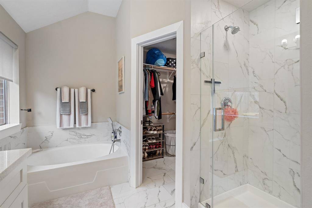 The primary bathroom also features a spacious tiled walk-in shower and a generous walk-in closet, offering both luxury and functionality.