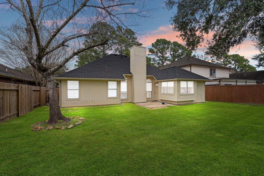 The fenced backyard offers a private oasis featuring beautiful landscaping and a mature tree, creating a serene and inviting outdoor space.