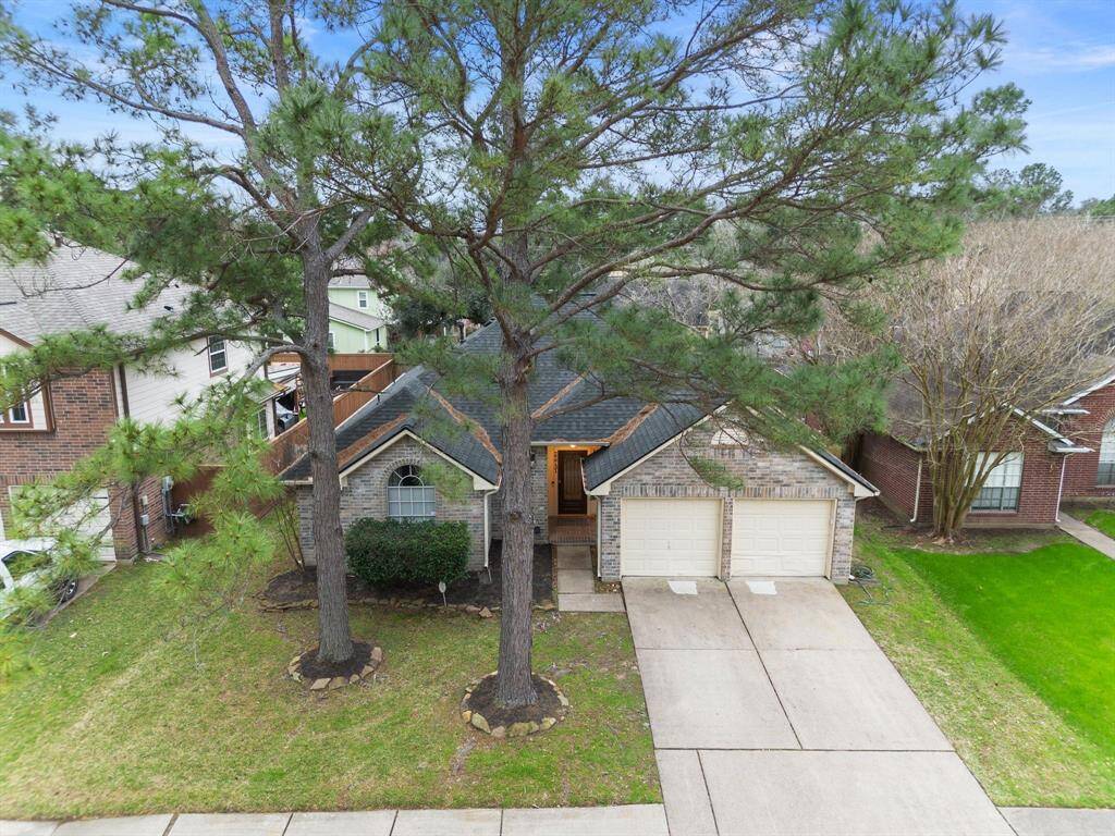 The front of this home boasts impressive curb appeal with two mature trees, a lush green lawn, beautifully maintained landscaping, and a spacious two-car garage.