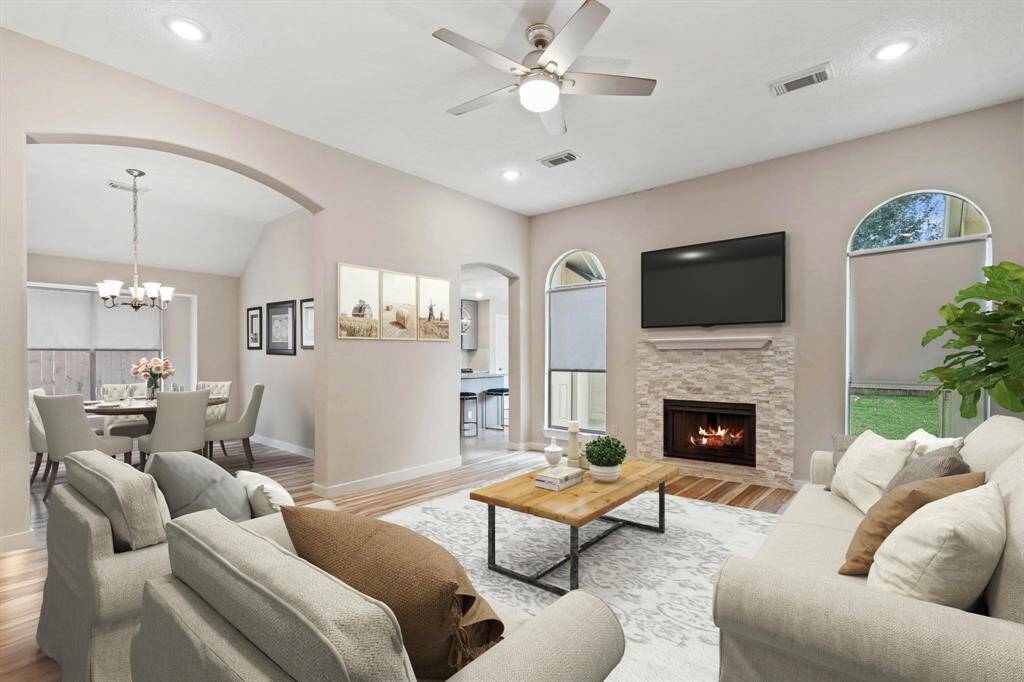 The living room offers a grand feel with soaring high ceilings, a cozy gas log fireplace framed by windows on both sides, and elegant recessed lighting that enhances the warm and inviting atmosphere. *Virtually Staged*
