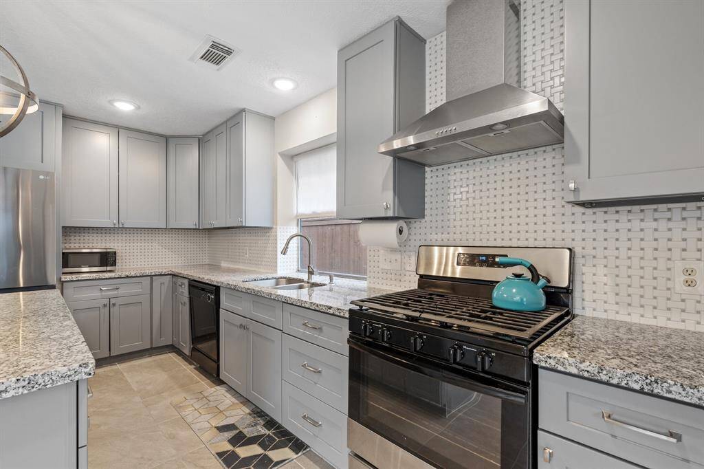 A close view of this amazing kitchen, featuring upgraded stainless steel appliances, a chefs 30" range hood and modern backsplash.