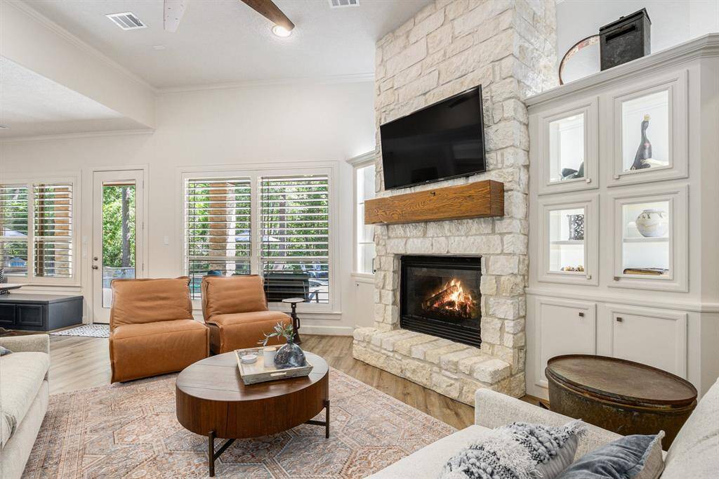 Stunning living room presents high ceilings, a cozy fireplace, gorgeous built-ins, and overlooks the backyard.