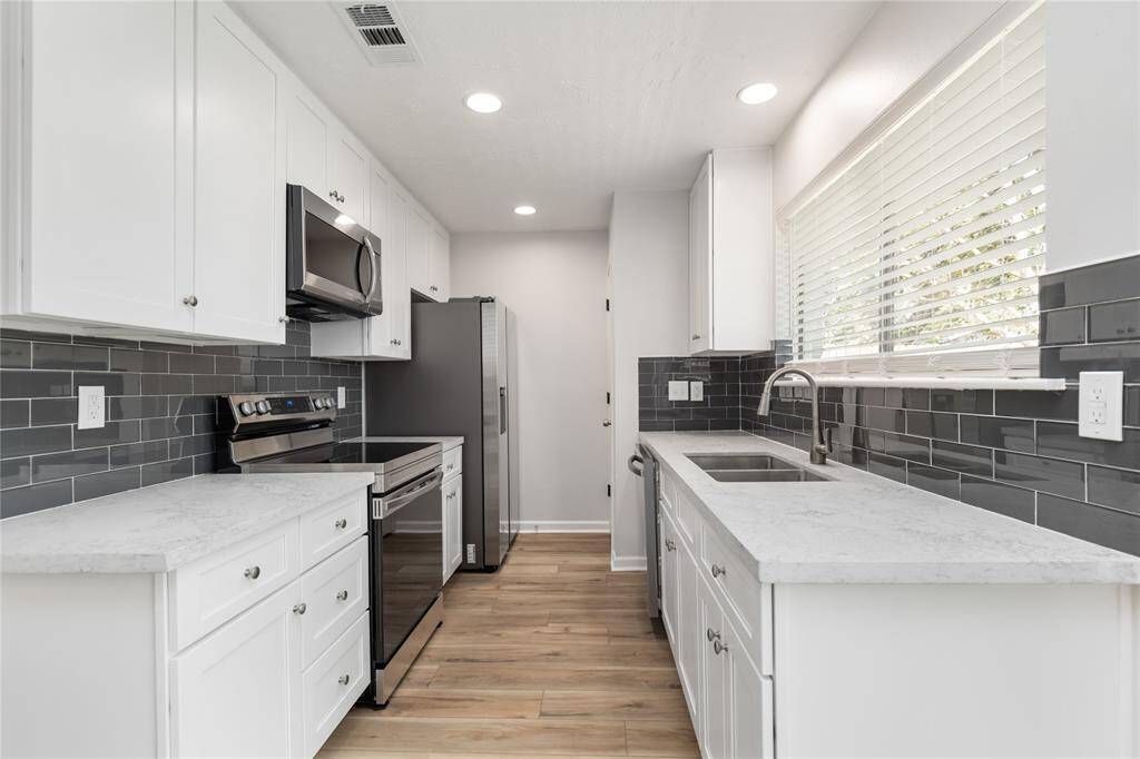 The beautifully Kitchen has brand new stainless steel appliances, quartz counters, a subway tile backsplash, and LED lighting