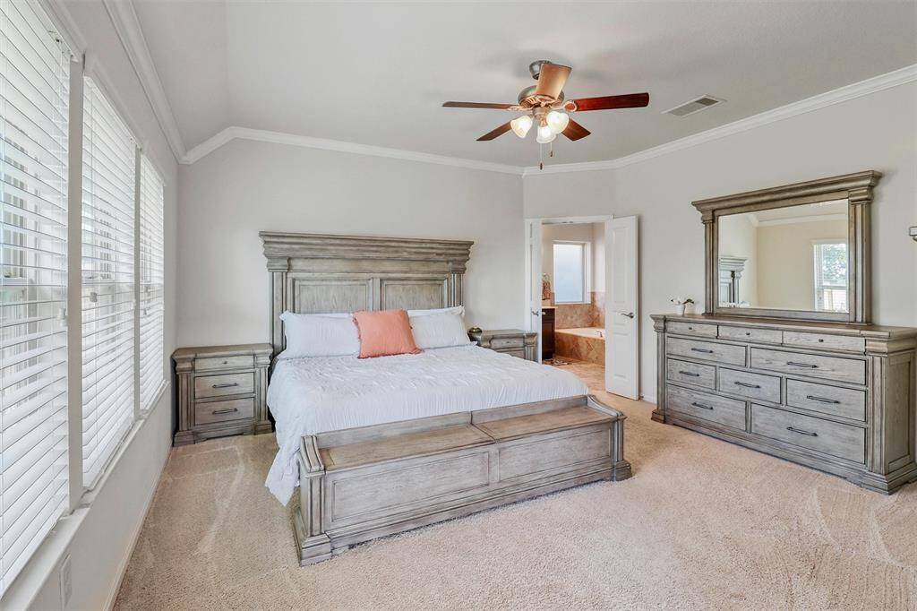 Welcome to your private sanctuary—this spacious first-floor primary suite invites rest and relaxation with soft carpet underfoot, elegant crown molding, and a soothing neutral color palette that complements any style.