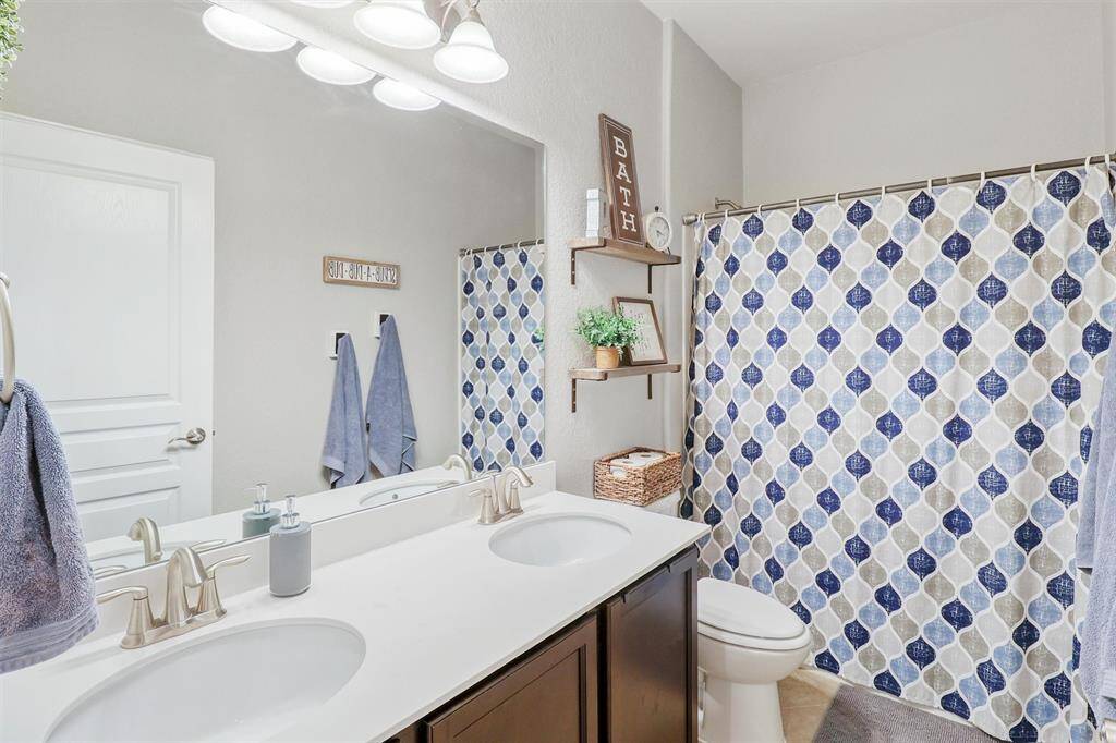 Stylish and functional, the guest bathroom offers a dual-sink vanity with sleek countertops, contemporary fixtures, and ample under-cabinet storage. A combined tub/shower adds versatility, making it perfect for guests or daily routines.