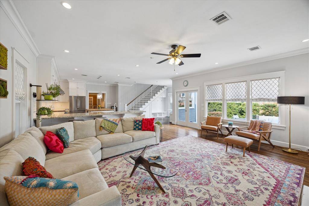 An open-concept layout connects the living room seamlessly to the kitchen and dining areas, with natural light pouring in through large windows and French doors leading to the backyard.