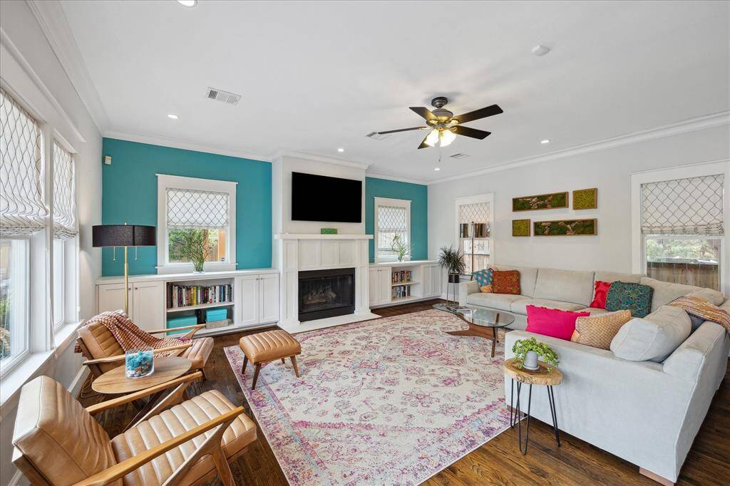 This spacious living room is anchored by a cozy gas fireplace flanked by built-in shelving and pops of teal accent walls, creating a colorful yet calming retreat for relaxing or entertaining.