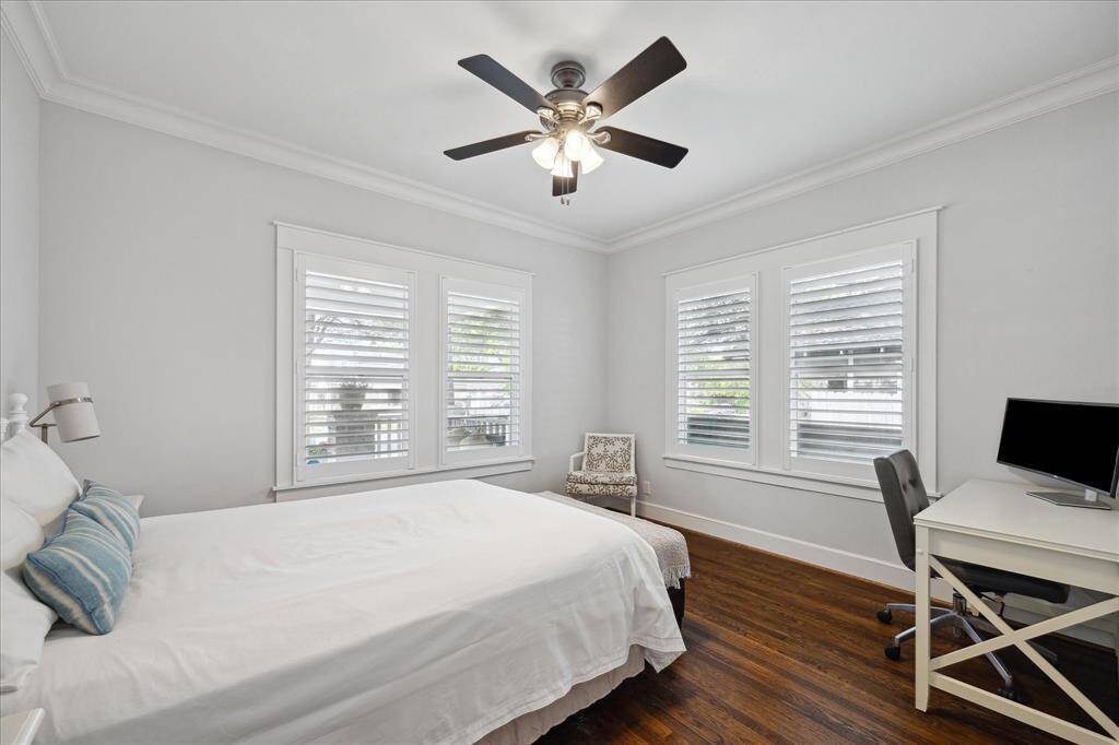 This serene first-floor bedroom features hardwood floors, plantation shutters, and a ceiling fan — perfect as a guest room, home office, or both.
