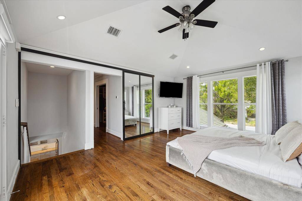 The spacious upstairs primary bedroom features vaulted ceilings, beautiful hardwood floors, and a wall of windows that flood the space with natural light and treehouse-like views.
