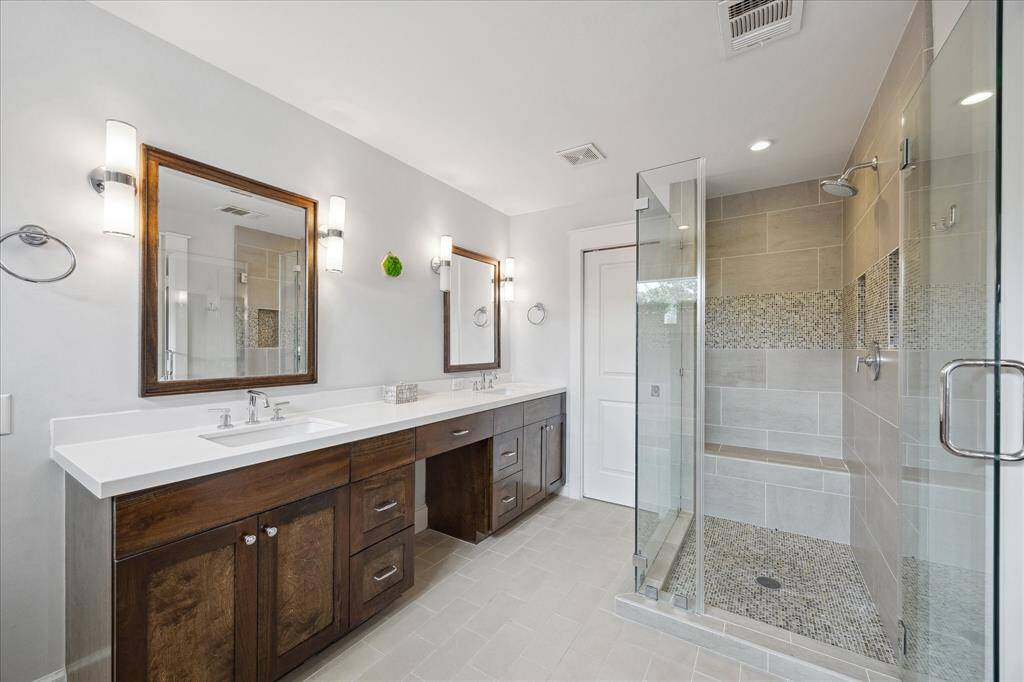 Enjoy the luxury of a double vanity and an oversized walk-in shower with a built-in bench and mosaic tile accents — the perfect blend of functionality and high-end style.