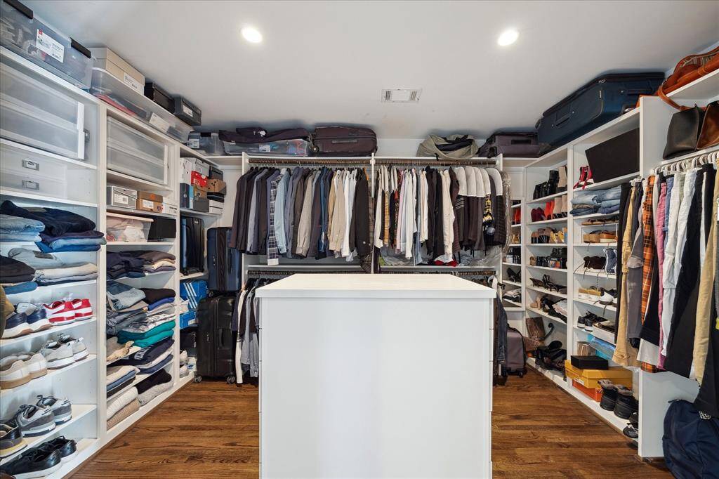 The expansive primary closet offers custom built-ins, open shelving, ample hanging space, and a center island with drawers — thoughtfully designed for maximum organization and everyday convenience.