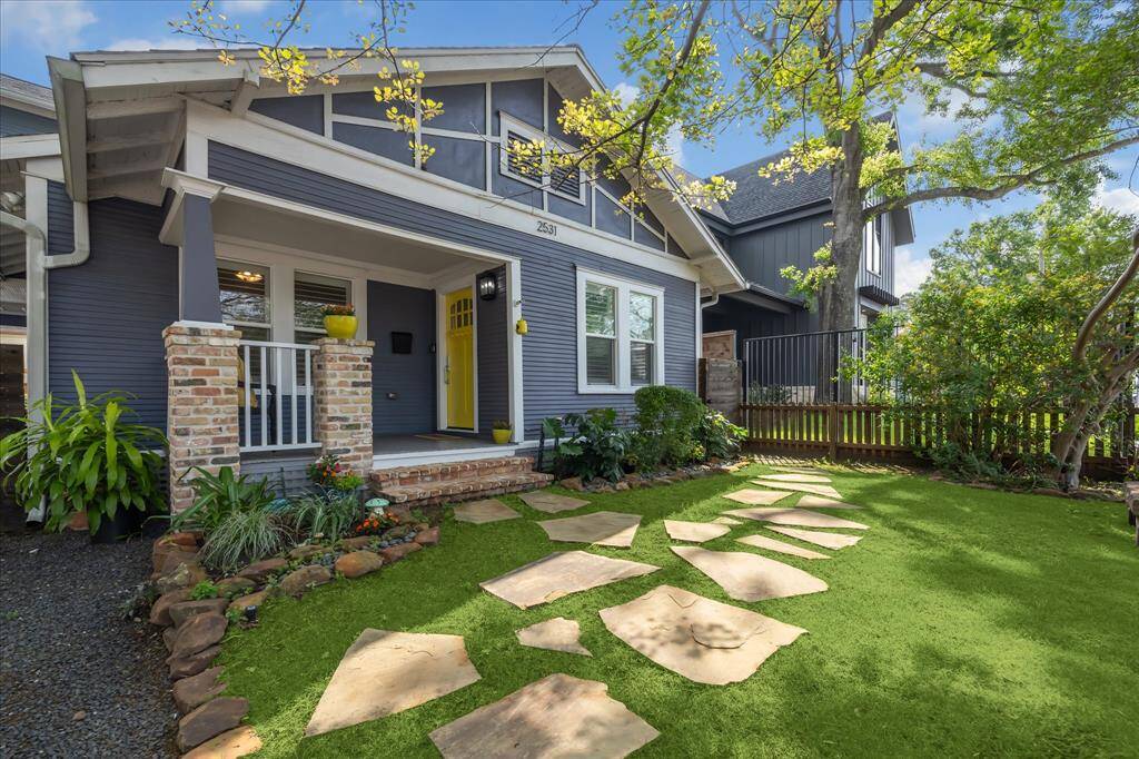A closer look at the inviting front porch and stone pathway leading to the entrance — perfect for morning coffee or evening relaxation under the shade of the trees.