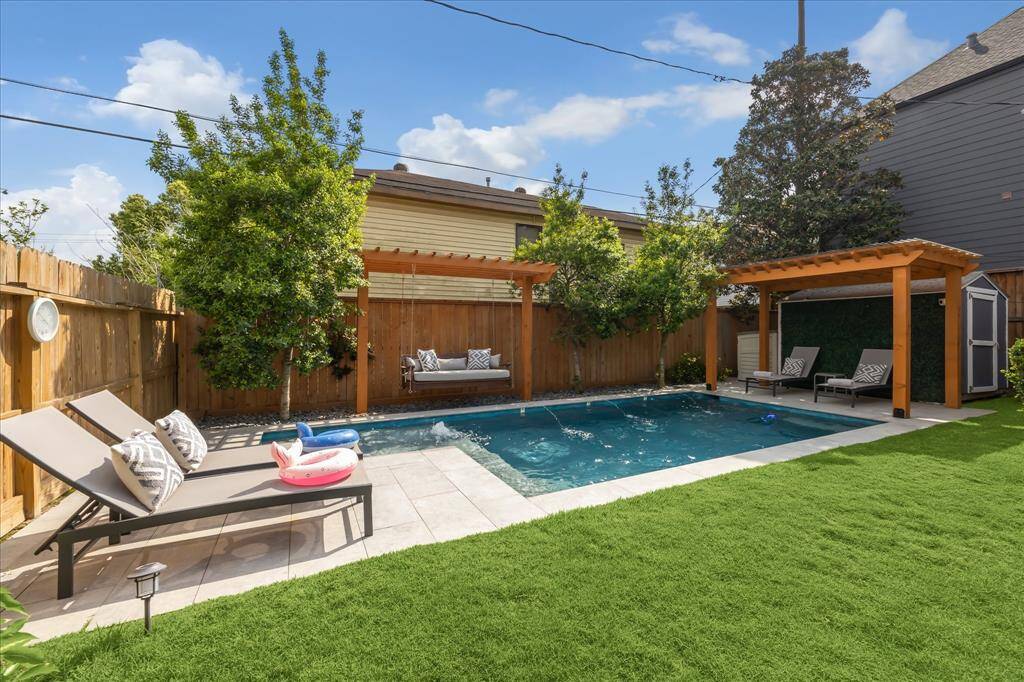 This backyard retreat features a sparkling pool with water features, flanked by two custom cedar pergolas.
