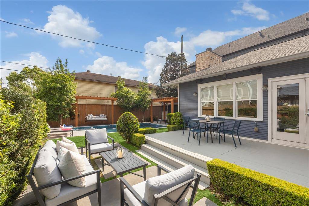 A view from the backyard seating area, showcasing a beautifully landscaped retreat with manicured hedges, lush turf, and a sparkling pool framed by dual pergolas—perfect for relaxing or entertaining.