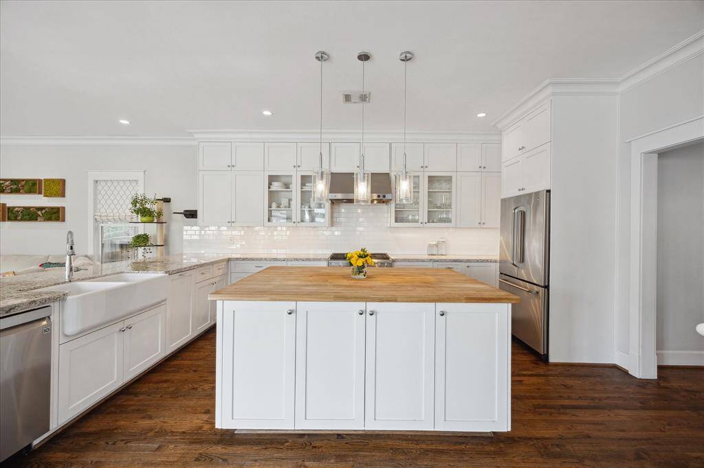 This bright and airy kitchen features timeless white cabinetry, granite countertops, and a spacious butcher block island — perfect for entertaining or everyday cooking.