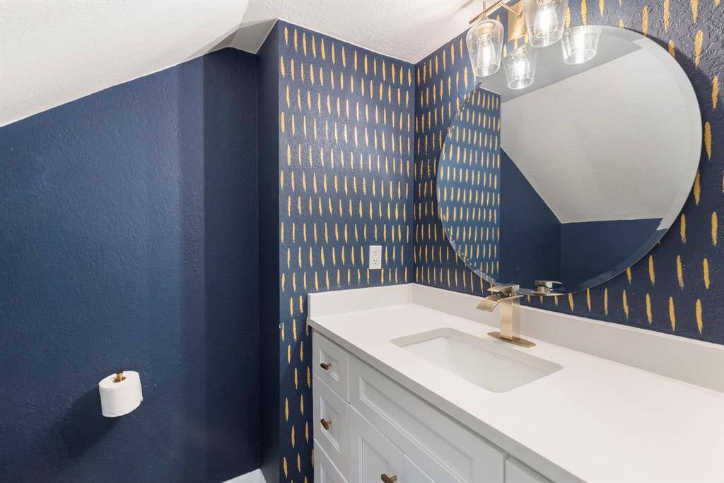 The gorgeous half-bath is hidden beneath the stairs and includes beautiful updates and custom paint.