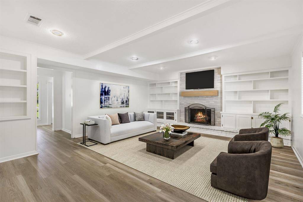 The living room is oversized and features recessed lighting, custom built-ins, beautiful beams, a cozy fireplace and a built-in wine fridge.