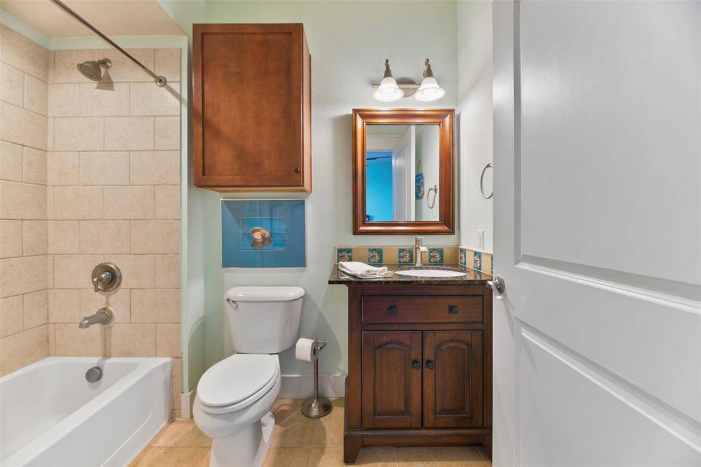 Private en-suite bathroom with a custom vanity and fun tiled backsplash, as well as a tub/shower combination with tile surround & nickel fixtures.