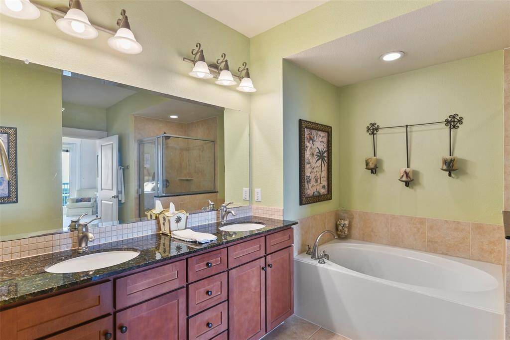 This spacious primary bathroom offers an expansive vanity with a granite counter top, undermount sinks, and nickel fixtures.