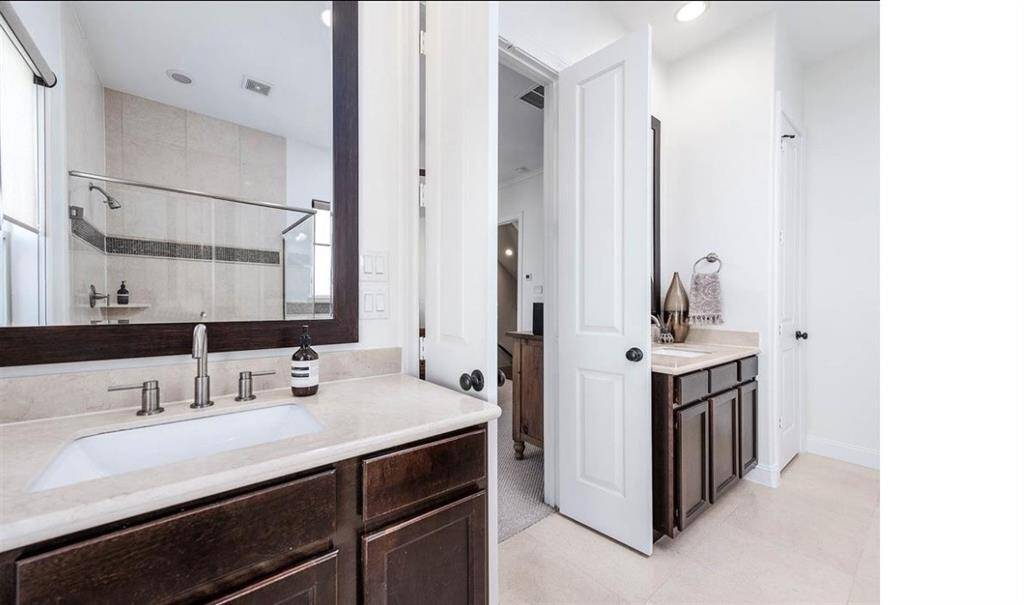Primary bathroom featuring french doors with double sinks. Includes water closet and second walk-in closet (not shown).