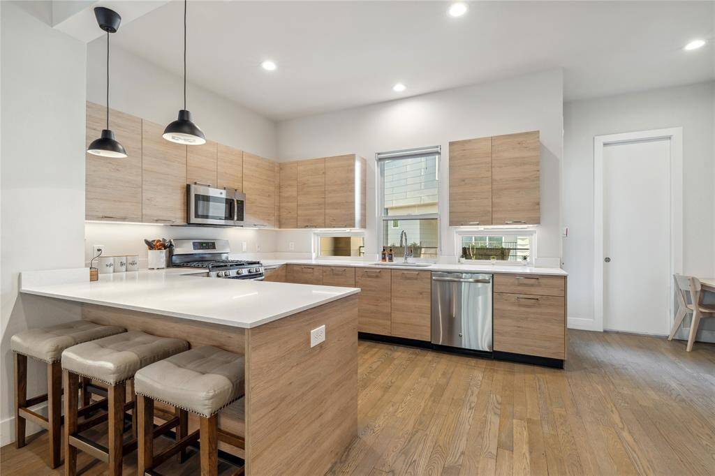 The kitchen features quartz countertops, a spacious island with bar seating, and sleek cabinetry that offers ample storage.